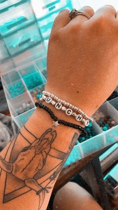 a person with a tattoo on their arm holding onto a plastic container filled with beads