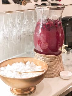 a pitcher filled with liquid sitting on top of a counter next to a bowl of ice