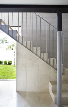 an open door leading to a set of stairs in a house with white walls and tile flooring