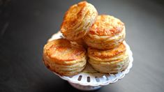 several small pastries are stacked on top of each other in a white bowl, sitting on a black table