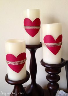 three white candles with red hearts on them