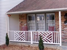 the front porch of a house with red chairs on it's railing and brick walls