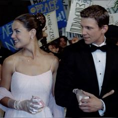 two people in tuxedos standing next to each other at an event with signs behind them