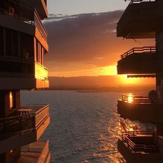 the sun is setting over some buildings by the water