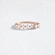 a gold ring with pearls and diamonds on the side, sitting on a white surface