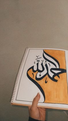 someone holding up a book with arabic writing on it