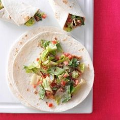 two tortillas with lettuce, tomatoes and other toppings on a white plate