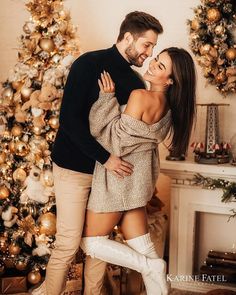 a man and woman standing next to each other in front of a christmas decorated tree