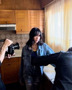 two people in a kitchen one is holding a camera