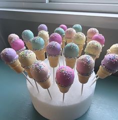 cake pops with sprinkles are arranged in a cupcake holder on a window sill