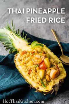 pineapple fried rice in a pineapple on a blue cloth with a spoon next to it