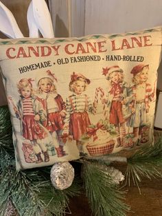 an old fashioned candy cane lane pillow sitting on top of a table next to christmas decorations