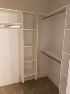 an empty walk in closet with white shelving