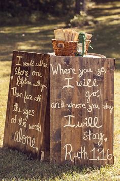 two wooden signs sitting on top of a grass covered field next to a basket filled with flowers