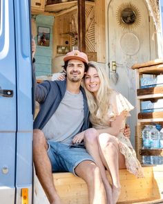 a man and woman sitting on the back of a blue truck with their arms around each other