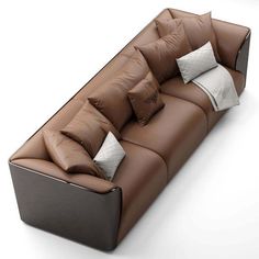 a brown leather couch with several pillows on the top and bottom, sitting in front of a white background