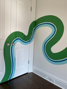 a room with a door and wall painted in green, blue and white swirls