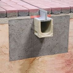 a cement box attached to the side of a brick wall with a concrete block around it