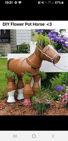 a horse shaped planter in the middle of a flower bed with purple flowers growing out of it