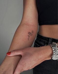 a close up of a person's arm with a flower tattoo on the wrist