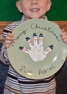 a young boy is holding up a plate with snowmen on it and the words merry christmas