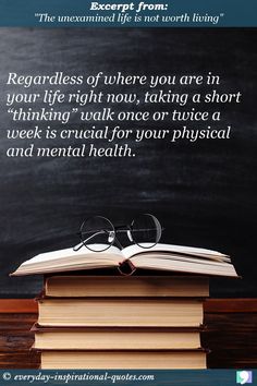 an open book sitting on top of a pile of books next to a blackboard