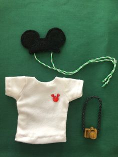 a white t - shirt with a red mickey mouse pin on it next to a black necklace