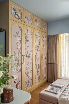 a living room filled with furniture and a window covered in floral wallpaper next to a couch