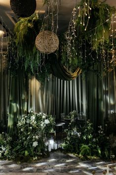 a room filled with lots of greenery and hanging lights