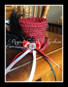 a red hat with black and white feathers on top of a wooden table next to a chair