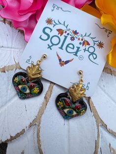 Infuse your style with a dash of Mexican charm with our hand-painted heart earrings. Each pair is meticulously crafted by skilled artisans, capturing the essence of Mexico's rich culture and artistic heritage.  Every piece is completely unique because of the detailed process that goes into creating it. The black lacquer is created by mixing in layers of dirt with a grease from the Cochinilla bug. The flowers are painted on with our finger tips using ground up natural pigments and linseed oil. To Artisan Heart Earrings As Gift, Artisan Heart Earrings For Pierced Ears As Gift, Artistic Heart Earrings As Gift, Artistic Heart-shaped Earrings For Gift, Hand Painted Earrings For Festivals, Hand Painted Earrings For Gift And Festivals, Artistic Dangle Heart Earrings As Gift, Artistic Dangle Heart Earrings For Gift, Artsy Heart-shaped Earrings For Gifts