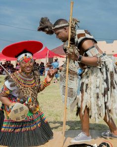 two people dressed in native american clothing standing next to each other