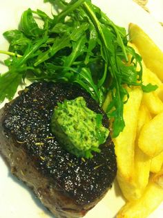 a plate with steak, fries and greens on it