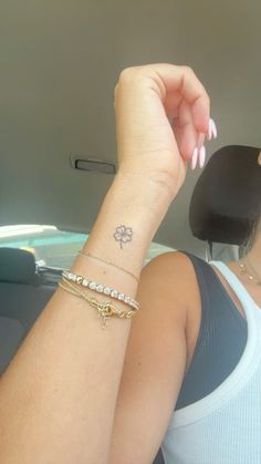 a woman in a car holding her arm up to the sunroof with a clover tattoo on it