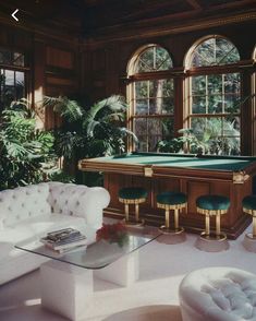 a living room filled with lots of furniture next to large windows and potted plants