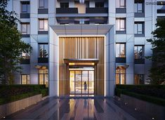 the entrance to an apartment building lit up at night with lights shining on the windows