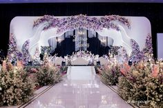 the entrance to a wedding ceremony decorated with flowers and greenery in front of a stage