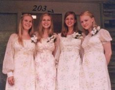 four women in dresses are posing for a photo outside the door to their wedding party