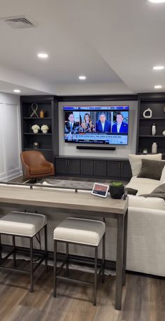 a large entertainment room with built in shelving and seating for four people, including a television on the wall