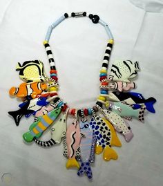 a necklace made out of ceramic fish on a white sheet with black and white stripes