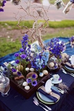 a table set with plates, silverware and purple flowers