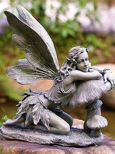 a statue of a fairy sitting on top of a rock