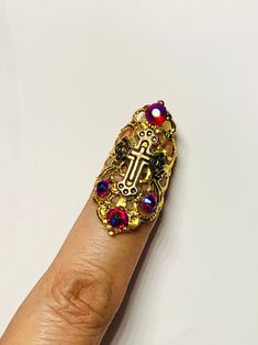 "Crystal claw ring, cross claw, nail claw, nail guard, nail ring, nail cover, metal nail guard, cross ring, metal nail cover, adjustable Small crystal claw, nail ring, nail tip. This claw ring is made in a gold color filigree metal (not real gold) adorned with a small cross charm in gold color and Siam red Ab Crystals it's sizable. This ring measures about 2\" on the widest part, its made of a very light alloy material. To adjust just squeeze gently until you make it your size, or until is comfortable for you to wear. All jewelry is 'costume' jewelry.  It is Not advised to be worn in water (showers or swimming).  This Metal may discolor over time if worn overnight or constantly." Nail Cover, Nail Rings, Nail Guards, Armor Ring, Claw Ring, Claw Nails, Nail Ring, Small Crosses, Cross Ring