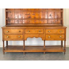 an old wooden dresser with two drawers and one shelf on the top, in front of a white wall