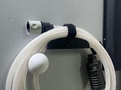 a white hose connected to a black and white object on the side of a wall