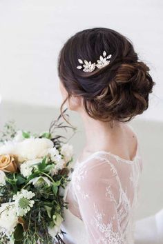 a woman holding a bouquet of flowers in her hand and wearing a wedding hair comb