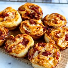 several mini pizzas sitting on top of a wooden tray