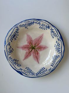 a blue and white plate with a pink flower on it