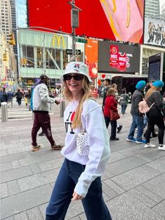 a woman standing on the sidewalk in front of a mcdonald's sign and people walking around