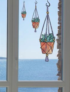 three hanging planters with succulents in them on a window sill